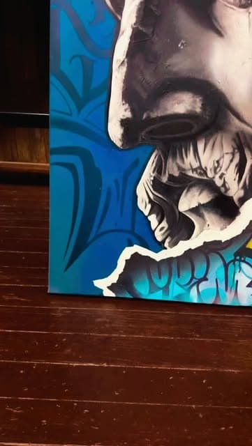 Detail of a painting in blue and black, a face above a carved skull.